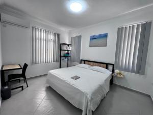 biała sypialnia z łóżkiem, biurkiem i oknami w obiekcie Sunshine Residence w mieście Poste Lafayette
