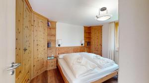 Schlafzimmer mit Holzwänden und einem Bett mit weißer Bettwäsche in der Unterkunft Truoch in Samedan