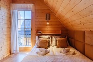 Łóżko w drewnianym pokoju z oknem w obiekcie Michałowy Sen Domki Zakopane w Zakopanem