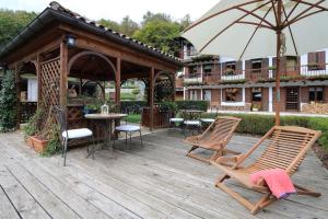 una terraza de madera con sillas y sombrilla en The Duck's Cottage, en Feltre