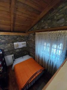 ein Schlafzimmer mit einem orangenen Bett in einer Steinwand in der Unterkunft Loutra Mountain Nature in Aridea