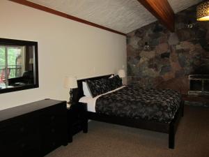 a bedroom with a bed and a stone wall at The Lodge At Skeena Landing in Terrace