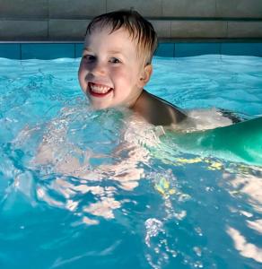 un jeune garçon nageant dans une piscine dans l'établissement Agluonenai Park Apartments, à Agluonėnai