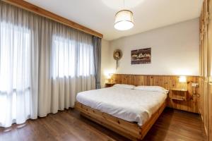 a bedroom with a bed and a large window at Stella Alpina in Campitello di Fassa