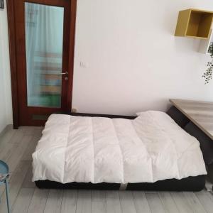 un letto bianco in una camera con pavimento in legno di Appartamento Galvani a Pordenone