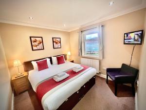 1 dormitorio con 1 cama grande y 1 silla en Glenachulish Bay with Hot Tub, en Glencoe