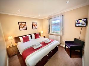 a bedroom with a large bed and a chair at Glenachulish Bay with Hot Tub in Glencoe