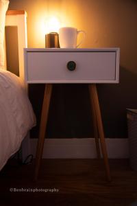 a nightstand with a cup and a lamp on it at No31 Apartment Cardiff in Cardiff