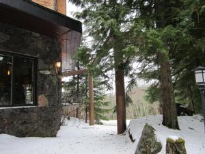 a building with snow on the ground next to a tree at The Lodge At Skeena Landing in Terrace
