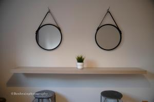 two mirrors hanging on a shelf with two stools at No31 Apartment Cardiff in Cardiff
