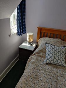 a bedroom with a bed with a lamp on a night stand at April cottage in Winchelsea