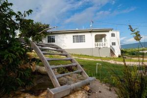 un puente de madera frente a un edificio blanco en Treasured Gem Hideaway, en Treasure Beach