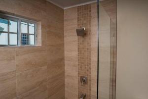 a shower with a glass door and a window at Treasured Gem Hideaway in Treasure Beach