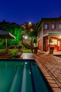 una piscina frente a una casa por la noche en Under the Boardwalk B&B Guest House, en Wilderness
