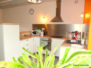 a kitchen with white cabinets and a clock on the wall at Maison rénovée avec jardin, animaux acceptés, climatisation, parking - FR-1-489-36 in Agonges +11 photos