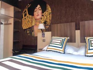 a bedroom with a bed with a painting on the wall at HOTEL ARVERNA VICHY - ClT'HOTEL in Vichy