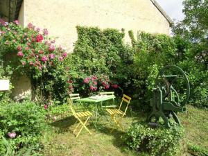 einen Garten mit einem Tisch, Stühlen und Blumen in der Unterkunft Gîte Dompierre-sur-Besbre, 5 pièces, 8 personnes - FR-1-489-109 in Dompierre-sur-Besbre