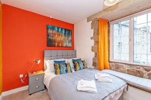 Bridge End Mill Apartments In Settle في سيتل: غرفة نوم بحائط ذات لهجة برتقالية وسرير