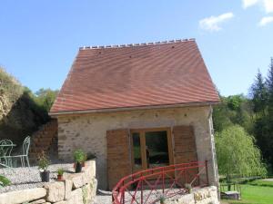 uma pequena casa com um telhado castanho e uma parede de pedra em Gîte Vernusse, 2 pièces, 2 personnes - FR-1-489-208 em Vernusse
