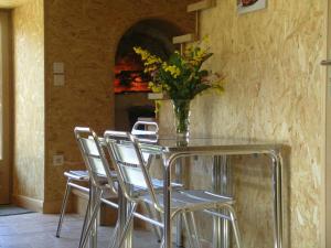 uma mesa de vidro com cadeiras e um vaso com flores em Gîte Vernusse, 2 pièces, 2 personnes - FR-1-489-208 em Vernusse