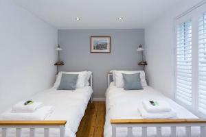 two twin beds in a room with white walls at Pickwick's Place By The Sea Broadstairs in Broadstairs