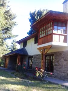een huis met een stenen gevel en ramen bij Ruca Quimei Malek in Bariloche