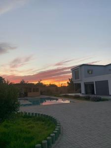 um edifício com piscina em frente a um pôr-do-sol em Magnifique villa avec piscine em Kenitra