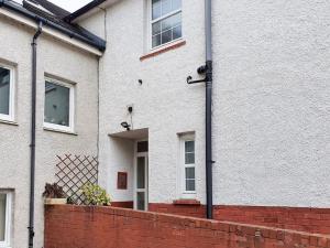 a white house with a brick fence in front of it at Parkgate Apartment - Near M90, Amazon, Edinburgh in Rosyth