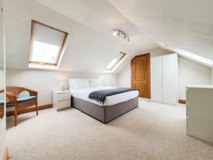 um quarto no sótão com uma cama e uma cadeira em Parkgate Apartment - Near M90, Amazon, Edinburgh em Rosyth