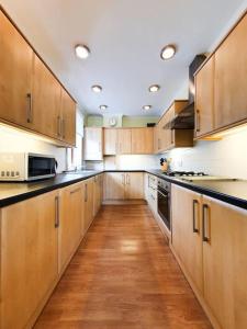 uma grande cozinha com armários de madeira e piso de madeira em Parkgate Apartment - Near M90, Amazon, Edinburgh em Rosyth