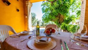 un tavolo con piatti e bicchieri e una bottiglia di vino di Cortijo Coracho Osuna by Ruralidays a El Saucejo