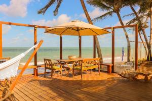 Qavi - Villa Jacumã #Luxo في جاكوما: سطح خشبي مع طاولة ومظلة على الشاطئ