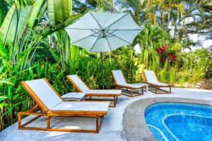 three lounge chairs and an umbrella next to a swimming pool at Tribe Boutique Hotel - Adults Only in Dominical