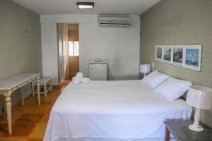 1 Schlafzimmer mit 2 Betten, einem Tisch und einem Schreibtisch in der Unterkunft Qavi - Villa Jacumã #Luxo in Jacumã