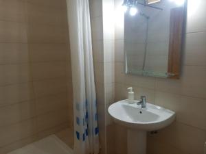 y baño con lavabo, espejo y ducha. en apartamentos la villa en San Sebastián de la Gomera