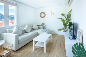 a white living room with a couch and a table at Mundaka Centre by Urdaibai Rentals in Mundaka