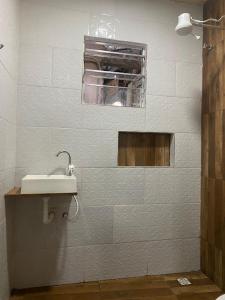a white bathroom with a sink and a window at Pesque pague pousada do Carlinho in Pinheiral