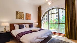 a bedroom with a bed and a large window at Sunkissed holiday homes Stylish seaside JBR 4BR apt near mall & tram in Dubai