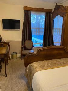 um quarto de hotel com uma cama, uma secretária e uma janela em The Croft Guest House em Stratford-upon-Avon