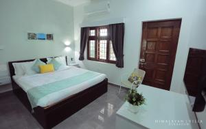 デヘラードゥーンにあるHimalayan Villaのベッドルーム1室(ベッド1台、デスク、窓付)