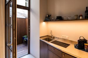 uma cozinha com um lavatório e uma porta para uma varanda em grätzlhotel Serviten em Viena