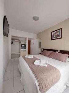 a bedroom with a large bed with a tv on the wall at Hotel Praiamar in Balneário Camboriú