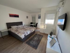 a bedroom with a bed and a desk and a television at Apartman Gavric in Doboj