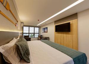 a bedroom with a bed and a flat screen tv at Gaeta Hotel in Guarapari