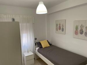 um pequeno quarto com uma cama com uma almofada amarela em Renovated and newly furnished 3 bedroom apartment em San Fernando