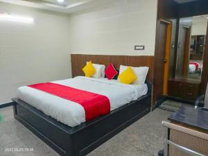 um quarto com uma cama grande com almofadas amarelas e vermelhas em Hotel New Maruthi Inn, LB Nagar em Hyderabad