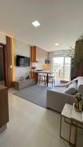 uma sala de estar com um sofá e uma cozinha com uma mesa em Apartamento em prédio residencial em FOZ DO IGUAÇU em Foz do Iguaçu