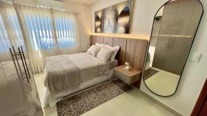 um pequeno quarto com uma cama e um espelho em Apartamento em prédio residencial em FOZ DO IGUAÇU em Foz do Iguaçu