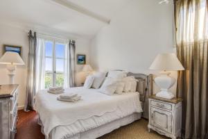 ein Schlafzimmer mit einem Bett mit weißen Laken und einem Fenster in der Unterkunft Villa Belle Époque - Welkeys in Grimaud + 10 Fotos