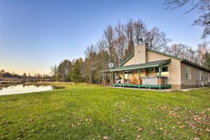 una casa con un estanque en medio de un campo en Sun-Dappled Cadillac Gem with Kayaks and Grill!, en Cadillac